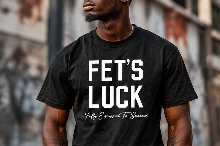 Male model wearing GET-ILL FET'S LUCK black graphic T-shirt with bold white lettering and Fully Equipped To Succeed slogan.