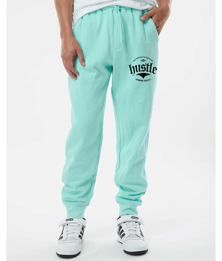 Light green "Hustle" sweatpants for sale, showing graphic detail on the leg.  "Hustle" brand light green sweatpants with a close-up of the leg graphic.