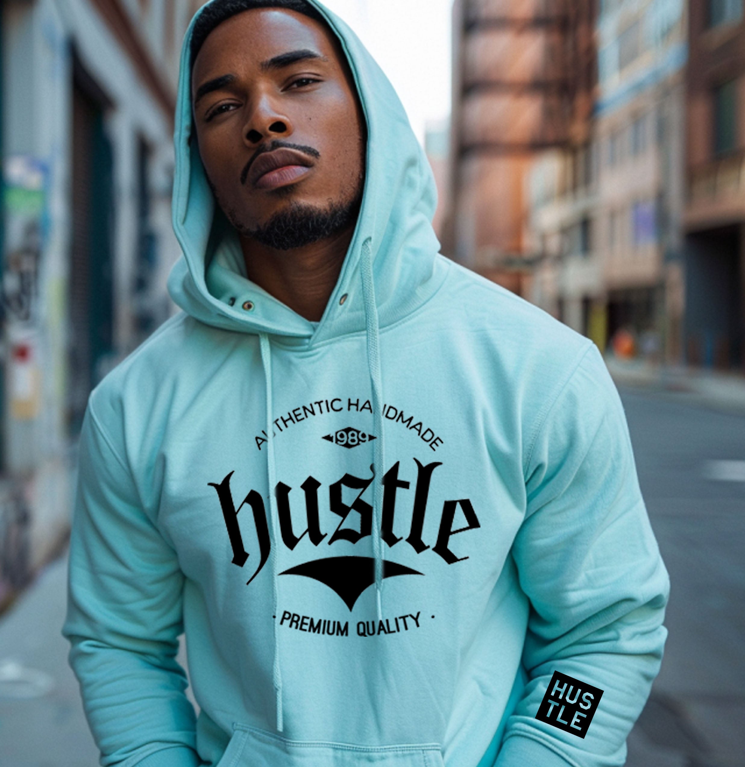 Close-up of light green 
hoodie on a person, showing the "hustle" graphic with "AUTHENTIC HANDMADE" and "PREMIUM QUALITY" text.